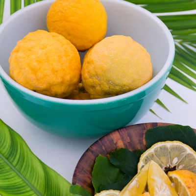 Teal bowl holding oranges, and a wooden plate holding sliced oranges.